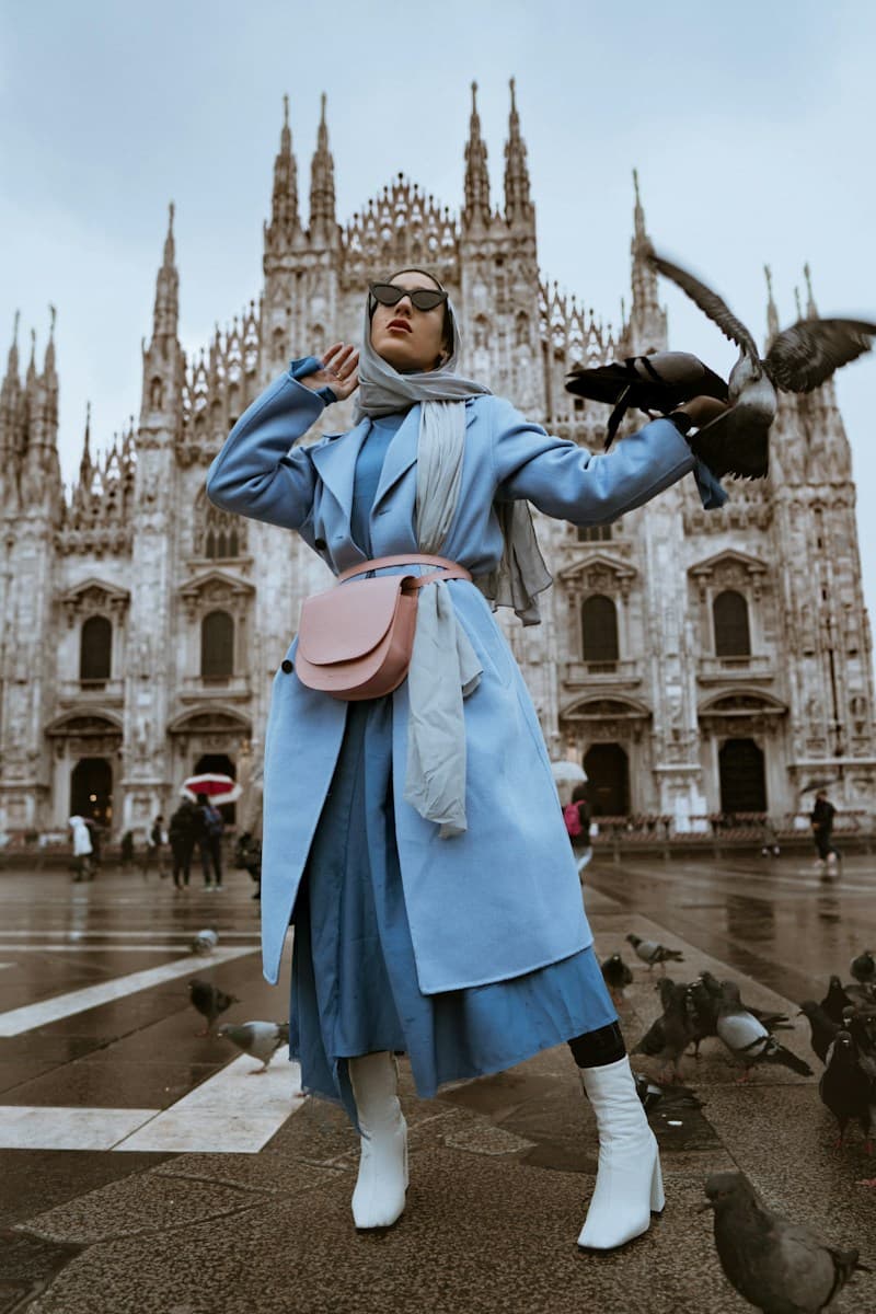 A statement powder-blue coat, white boots, and a pink crossbody bag in Milan