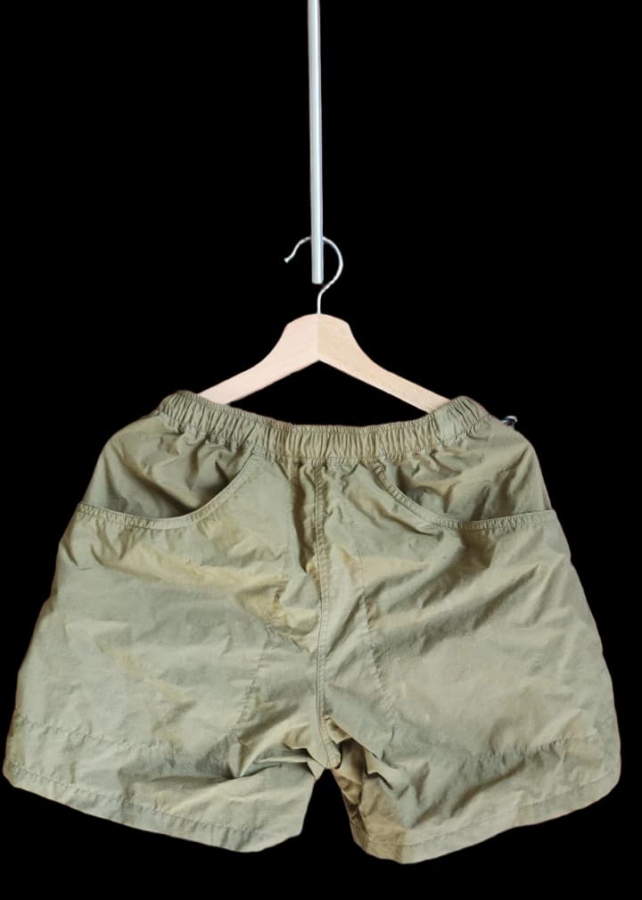 Olive green shorts with an elastic waist on a wooden hanger